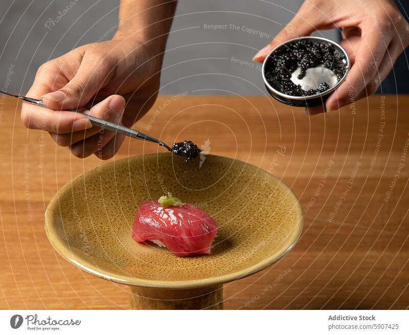 Adding caviar to sushi on a textured plate chef hand garnish dish culinary skill preparation cuisine japanese food seafood fish gourmet fresh nigiri decoration