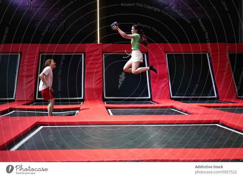 Friends enjoying a fun day at a trampoline park woman jumping recreation leisure friends friendship active activity bounce playful enjoyment indoor sport