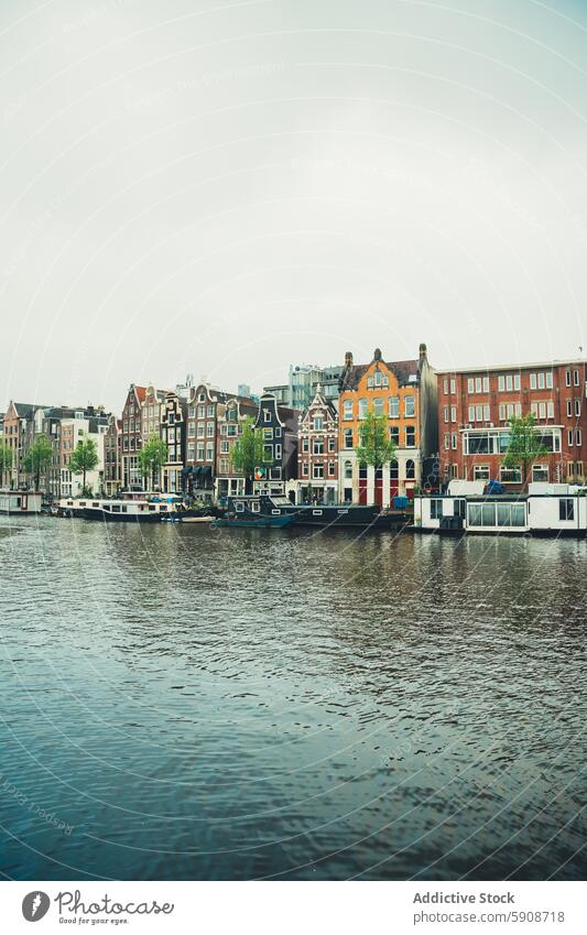 Tranquil Amsterdam canal with iconic narrow houses amsterdam netherlands water boat architecture travel city urban europe dutch facade reflection sky cloudy