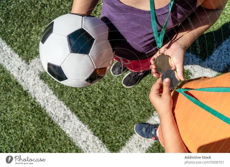 Children exchange medals and hold a soccer ball on playing field child sport team teamwork sportsmanship overhead view game competition win victory friendship