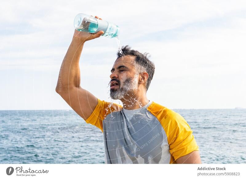 Indian man cooling off with water on a summer day by the sea indian refreshment sunny outdoor hydration health leisure relaxation hot eyes closed temperature