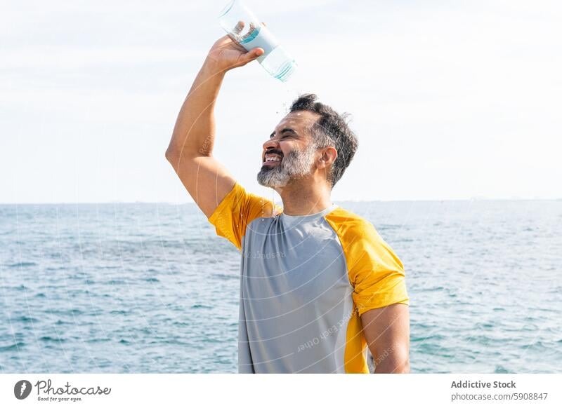 Indian man cooling off with water on a summer day by the sea indian refreshment sunny outdoor hydration health leisure relaxation hot eyes closed temperature