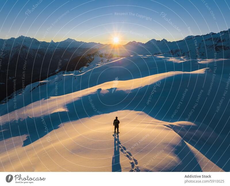 Lone traveler trekking through snowy Swiss Alps at sunset swiss alps winter mountain solitude adventure landscape nature outdoor cold pristine hiker trekker