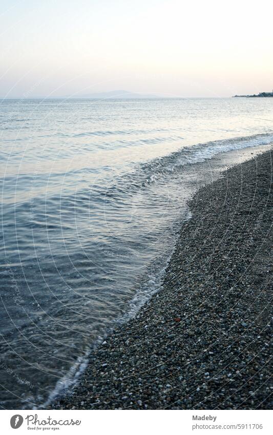 View from the beach in Altinoluk in the romantic light of the setting sun on the Gulf of Edremit on the Aegean Sea in the province of Balikesir in Turkey