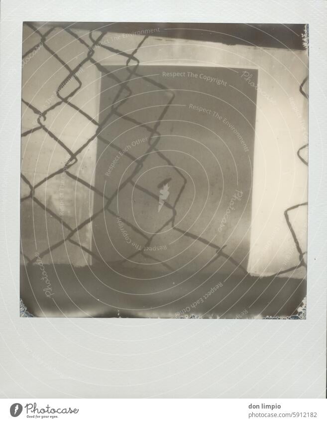 Wire mesh fence and a notepad Notepad Wire netting fence Wire fence Fence Safety Deserted Detail Exterior shot Black & white photo Polaroid Barrier Protection