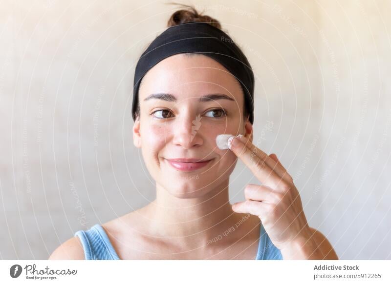 Woman applying facial cream as part of self-care routine woman moisturizing facial care bathroom skincare face moisturizer health beauty wellness female young