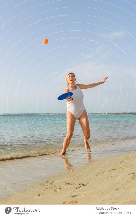 Woman playing paddle ball on a sunny beach mother italy italian seaside sand summer vacation fun holiday family swimwear playful joy clear sky water ocean coast