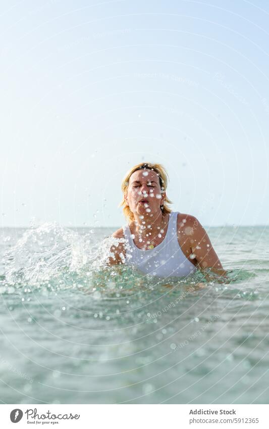 Woman splashing in the water at Italian beach woman italy sea swimming summer vacation holiday swimsuit white bright sunlight clear blue sky vibrant outdoor