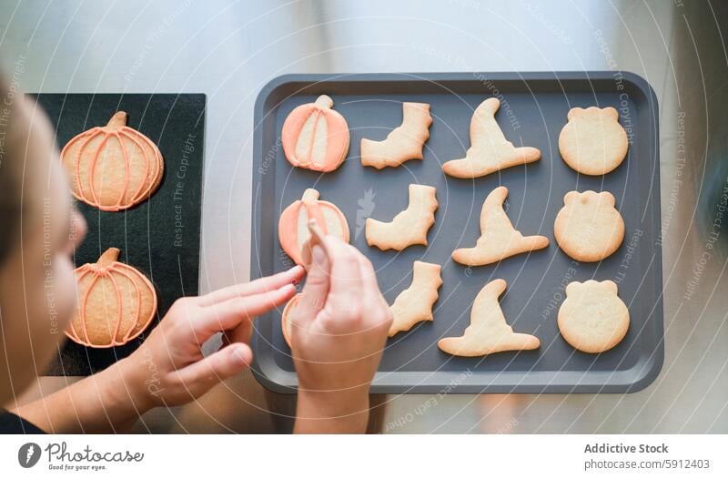 Decorating homemade Halloween cookies on a baking tray halloween decoration pumpkin witch hat kitchen holiday treat festive october baked goods pastry culinary