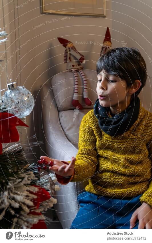 Boy in yellow sweater decorating the Christmas tree boy christmas tree decoration holiday festive cozy celebrate joy indoor season winter child kid male home