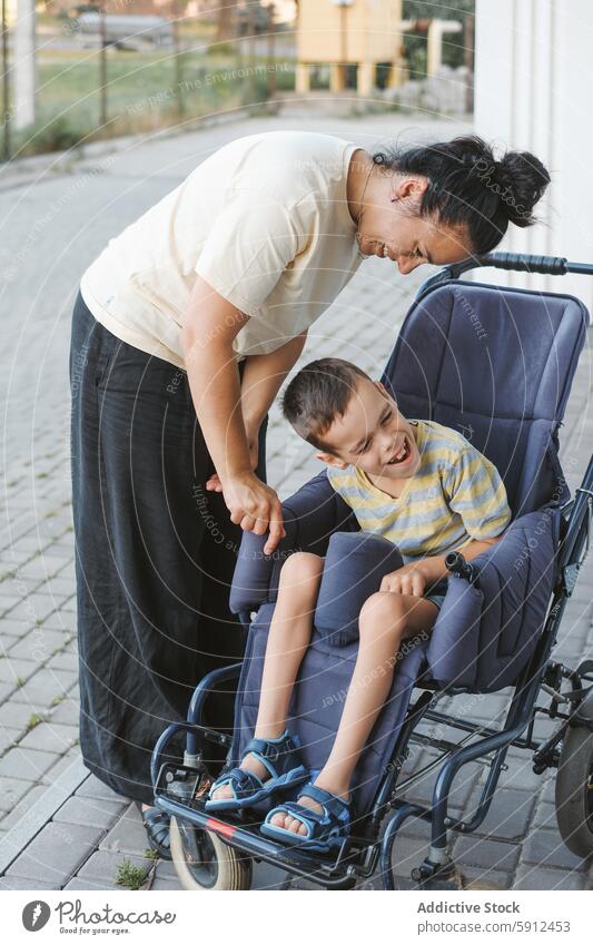 Mother bonding with son with cerebral palsy in wheelchair mother outdoors smiling care love disability interaction familial support health affection connection