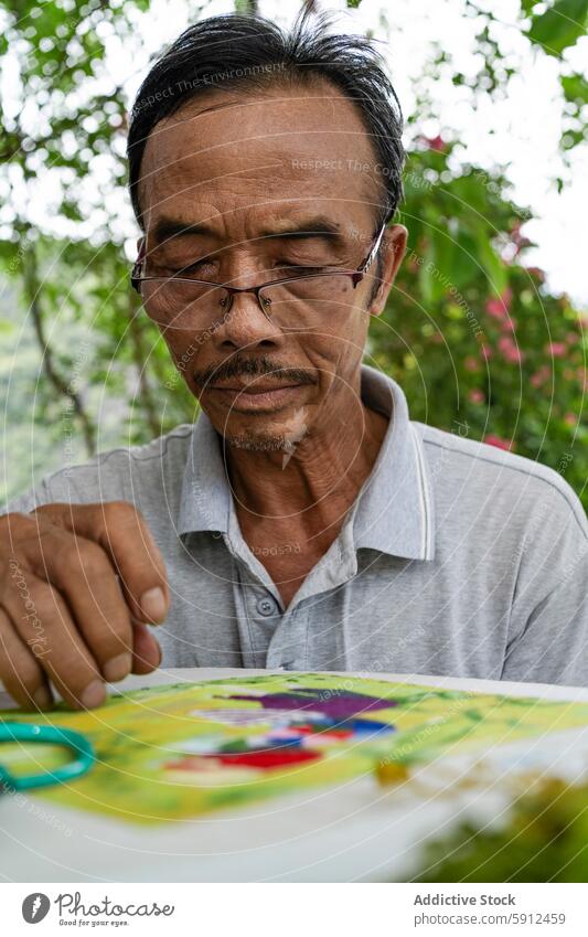 Elderly Vietnamese man sewing a colorful fabric vietnamese elderly craftsmanship outdoor traditional hand-stitching focus male culture skill hobby textile