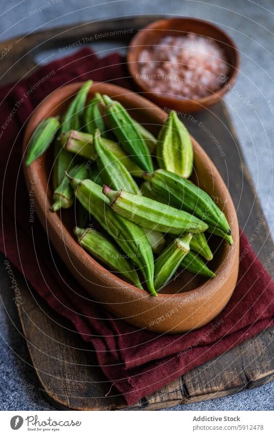 Raw bamia pods in a rustic bowl, ready for Mediterranean cooking okra raw vegetable wooden kitchen pink salt himalayan salt mediterranean cuisine fresh uncooked