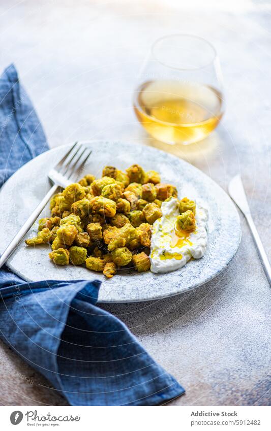 Fried bamia with sour cream sauce, dill, and garlic on plate fried mediterranean food dish wine glass white wine cuisine vegetable traditional snack meal