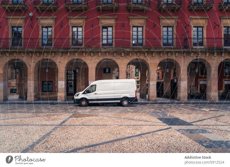 Delivery van parked in historic plaza in Gijon, Spain gijon spain delivery van white van cobbled red building arches vehicle architecture city urban transport