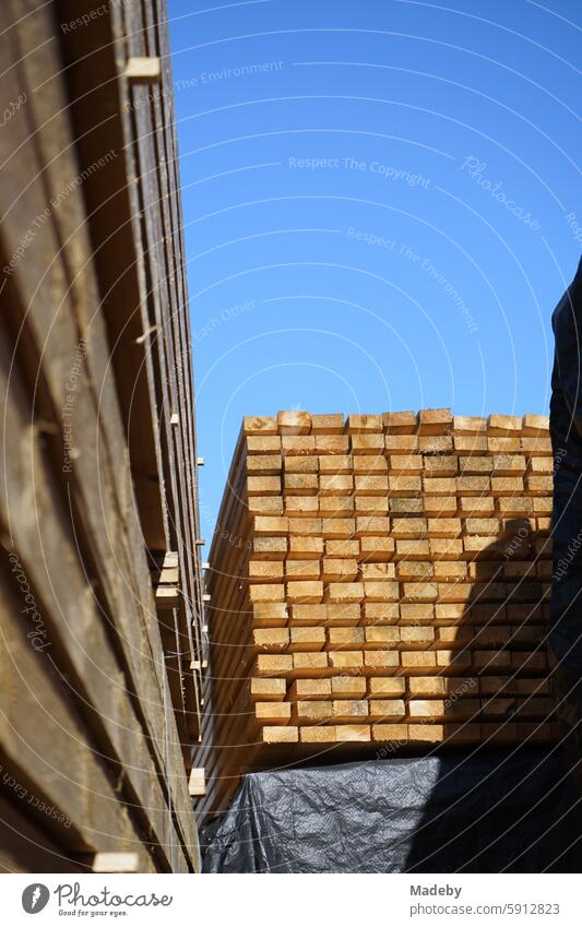 Stacked squared timber in the warehouse of a carpentry and joinery workshop for construction and handicrafts against a blue sky in the sunshine in Adapazari in the province of Sakarya in Turkey