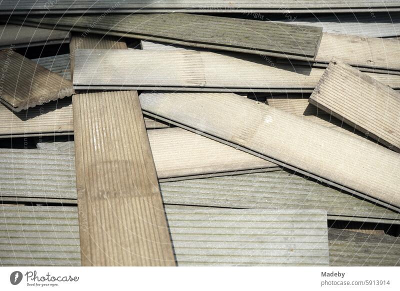 Old boards, planks and panels in beige and natural colors as building material or bulky waste for recycling in a front garden near Sonnenschein in Wettenberg Krofdorf-Gleiberg near Gießen in Hesse