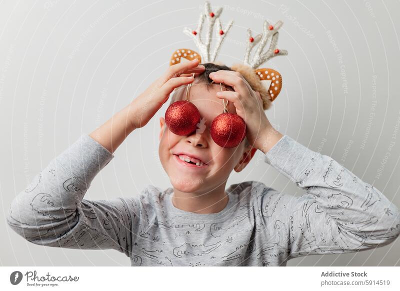 Young boy playing with Christmas ornaments christmas red playful festive holiday child eyeglasses background cheer joy fun decoration seasonal winter antler