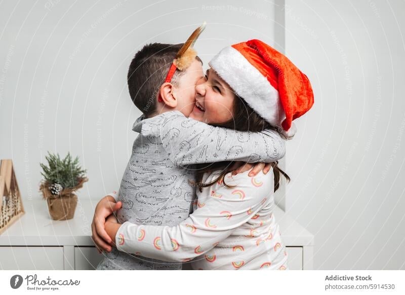 Joyful kids hugging in Santa hats during Christmas christmas santa hat joy festive child love family season celebration happiness sibling affection cheerful