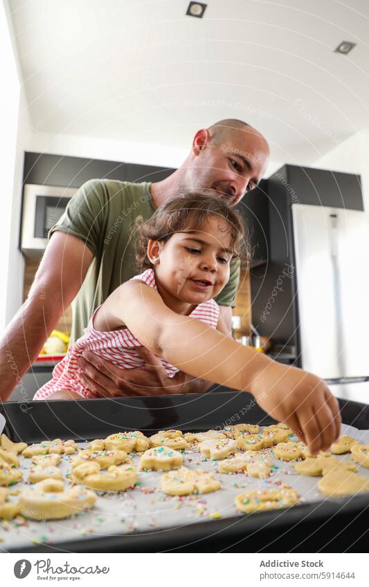 Father and daughter baking cookies together in kitchen father family teaching parent child cooking bonding oven tray home indoor fun happiness casual learning