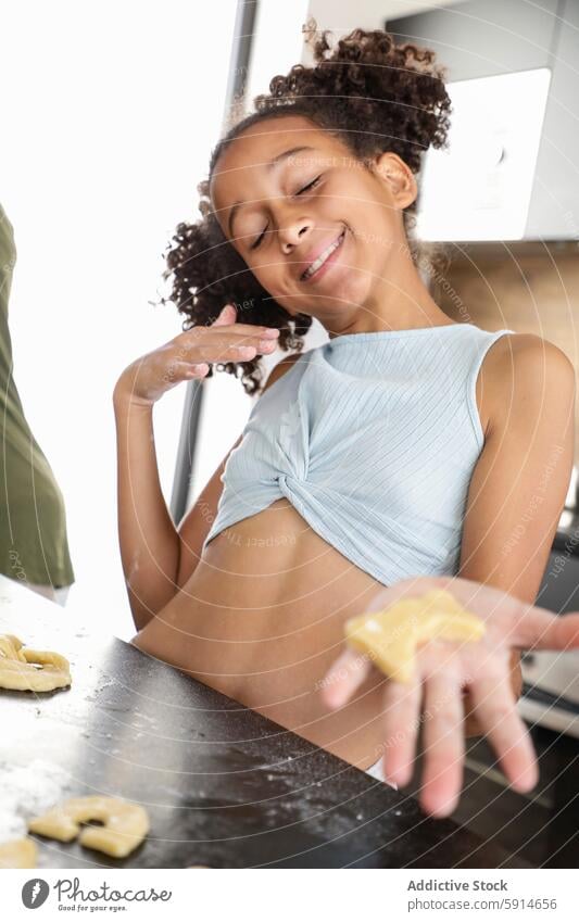 Young girl having fun baking cookies in the kitchen smile flour joy curly hair child dough homemade cooking indoor freshness playful happiness activity leisure