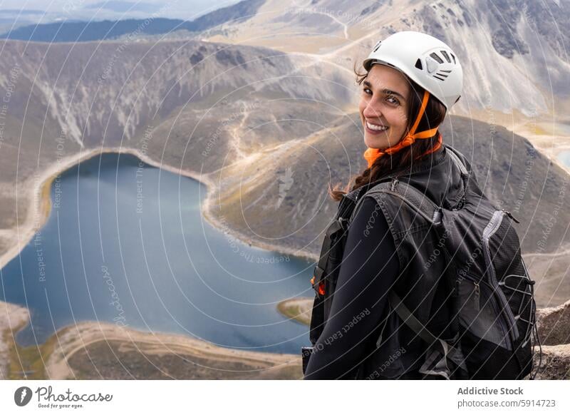 Smiling female hiker with helmet overlooking a dormant volcano woman lake mountain adventure outdoor nature sport smile looking at camera travel safety gear