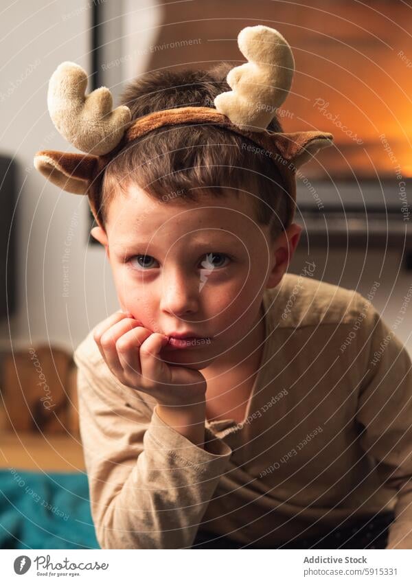 Young boy in reindeer antlers looking thoughtful child christmas cozy indoor celebration holiday festive young winter season decoration cute youth pensive quiet