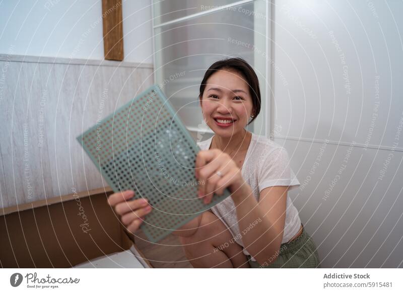 Asian woman happily assembling furniture at home asian assembly diy interior cheerful smile modern project metal grid cabinet casual lifestyle activity