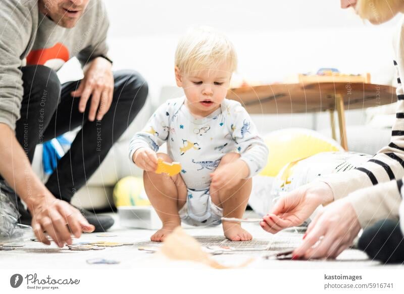 Parents playing games with child. Little toddler doing puzzle. Infant baby boy learns to solve problems and develops cognitive skills. Child development concept