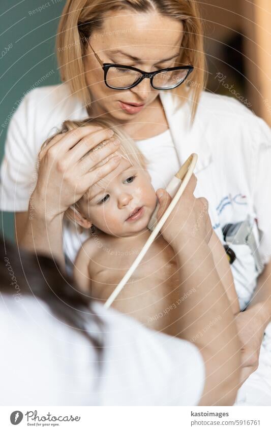 Small child being checked for heart murmur by heart ultrasound exam by cardiologist as part of regular medical checkout at pediatrician. medicine healthcare