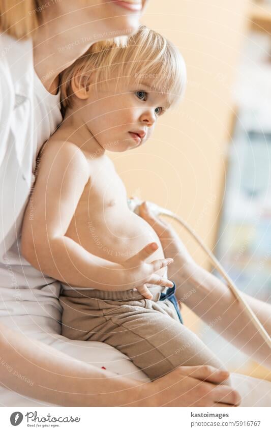 Small child being checked for heart murmur by heart ultrasound exam by cardiologist as part of regular medical checkout at pediatrician. medicine healthcare