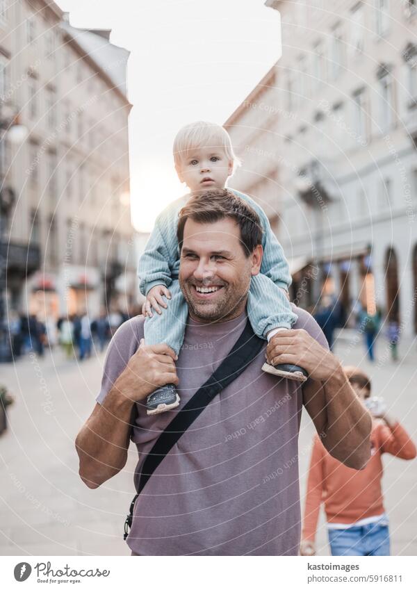 Portrait of smiling father carrying his toddler child piggyback around city on family vacations. Happy father's day. fun happy son outdoors parent lifestyle man