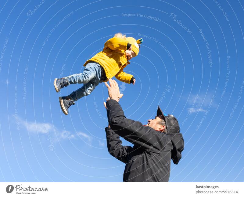 More, more,...dad, that's fun. Happy young father throws his cute little baby boy up in the air. Father's Day, Father and his son baby boy playing and hugging outdoors in nature in fall.