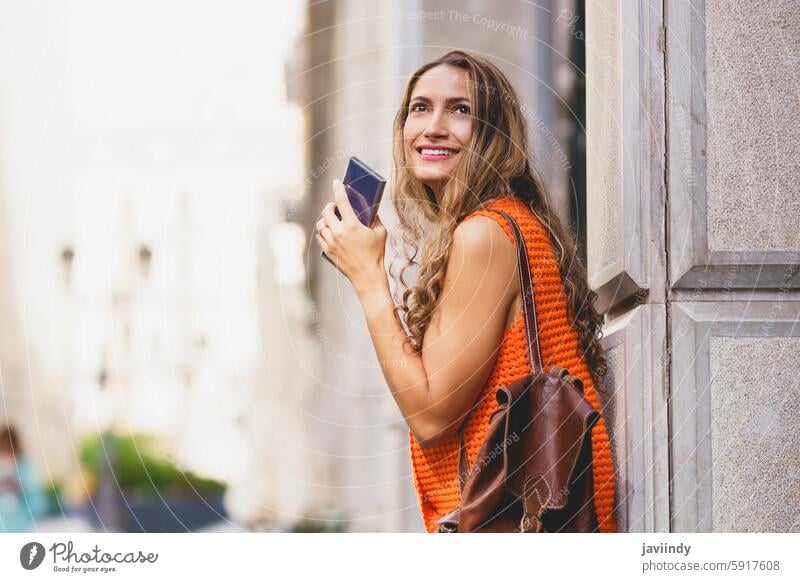 Woman holding a mobile and looking up visiting a city latin beauty woman mobile phone urban street outdoor lifestyle ethnic tourist exploration adventure