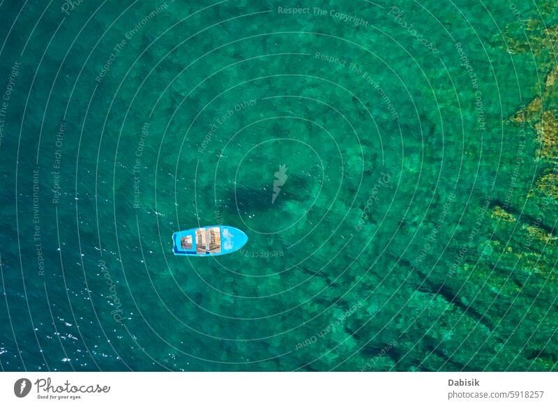 Small fishing boat is floating on calm turquoise water surface on summer day sea ocean blue travel vacation tourism top view aerial drone background coastline