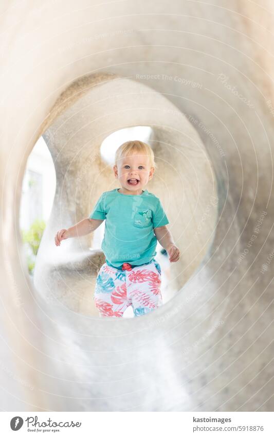 Child playing on outdoor playground. Toddler plays on school or kindergarten yard. Active kid on stone sculpured slide. Healthy summer activity for children. Little boy climbing outdoors.