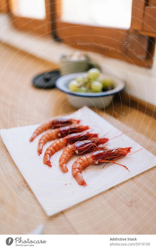 Fresh prawns on chopping board with blurred dishes in background seafood fresh vibrant wooden table grapes bowl culinary gourmet ingredient kitchen healthy