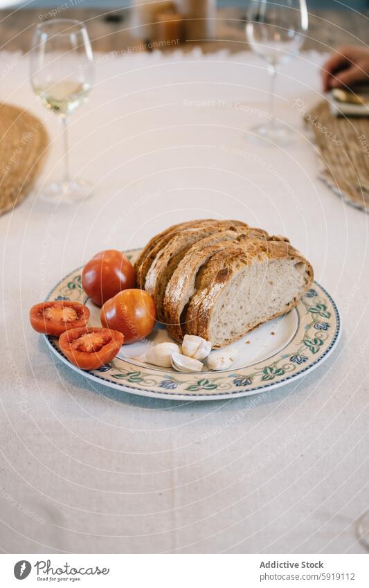 Elegant dining setup with freshly sliced bread and tomatoes table garlic wine glass plate decorative meal sophisticated ripe clove elegant background setting