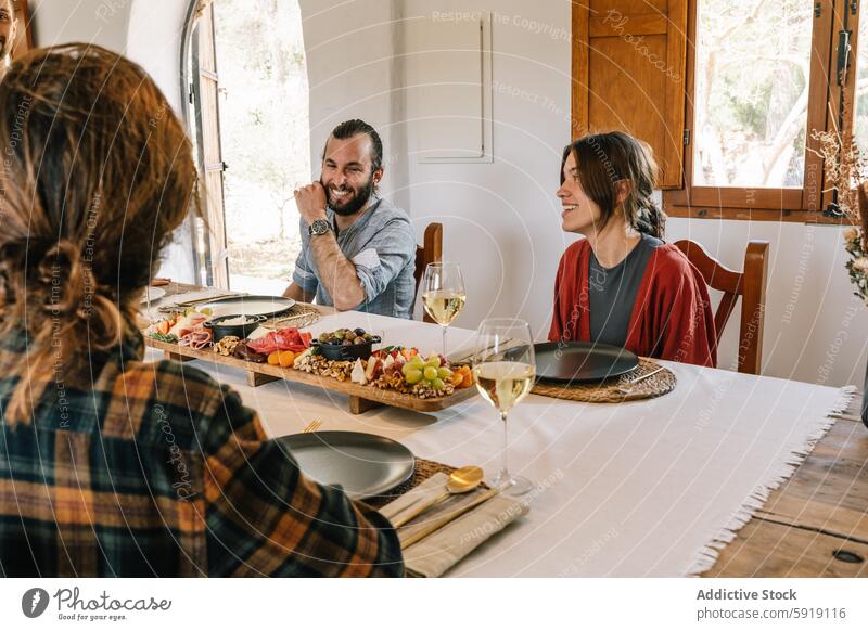 Friends enjoying a meal with private chef at home friends dining food table wine women man laughter smiling looking away looking down enjoyment indoor cozy