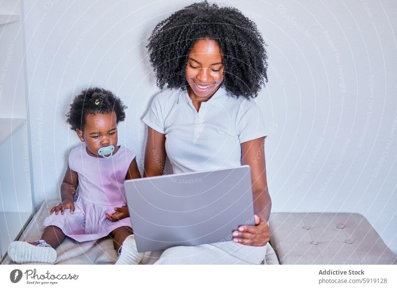 Mother and toddler engaging with laptop in a light room woman child mother daughter computer education learning technology family home indoor sitting pacifier