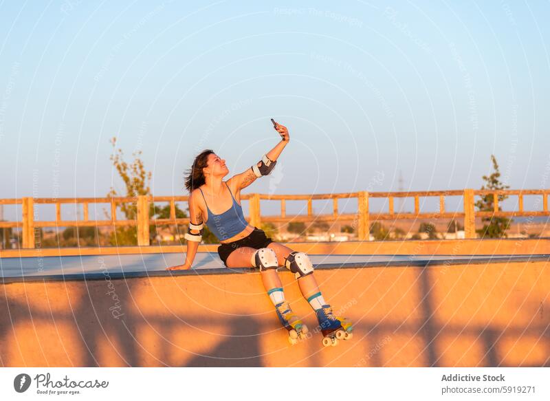 Young woman roller skating and taking a selfie at sunset roller skate skate park sportswear safety gear golden hour summer outdoor leisure recreation young