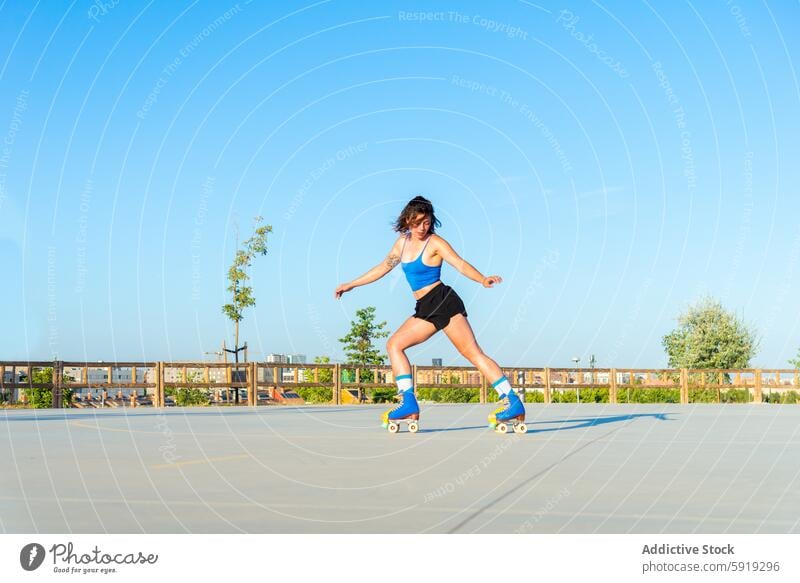 Young woman roller skating in a sunny outdoor skate park blue sky activity sport roller skates balance skill athletic wear summer recreation leisure youth