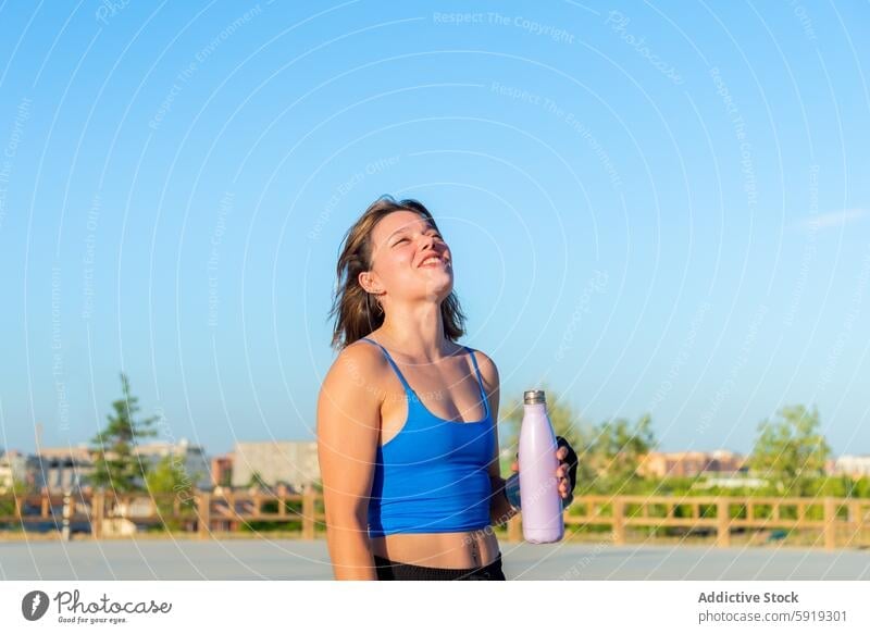 Young woman enjoying a break at a skate park roller skating water bottle sunny blue sky smiling cheerful young outdoor leisure sport roller skate fun active