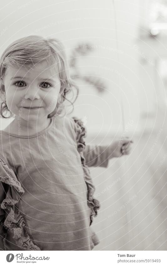 little girl smiles into the camera Girl Portrait of a young girl Black & white photo curly hair Looking into the camera Smiling smilingly Smiling face big eyes