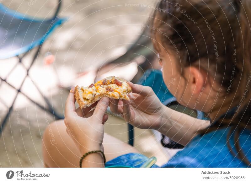 Young unrecognizable woman holding a slice of pizza and Enjoying a Campfire Meal outdoors camper campfire meal nature campsite cuisine enjoyment focus food