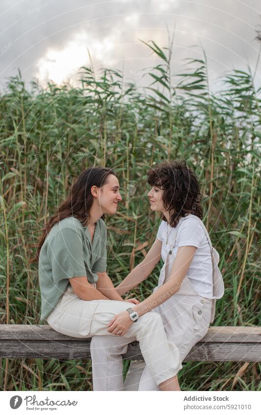 Lesbian couple interacting on fence against plants girlfriend same sex relationship love romantic spend time weekend countryside women lesbian embrace natural