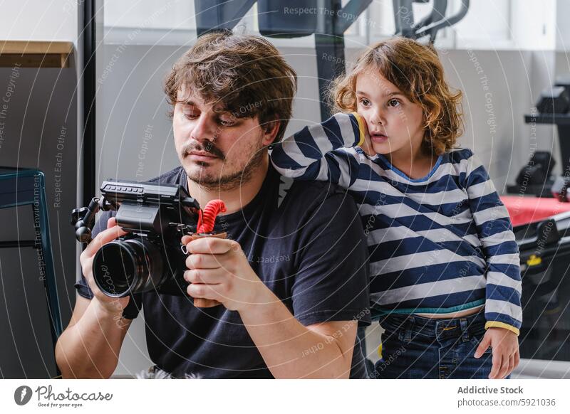 Father and child sharing a moment with a camera man curiosity leaning shoulder looking bonding technology video equipment filmmaker attention learning watching