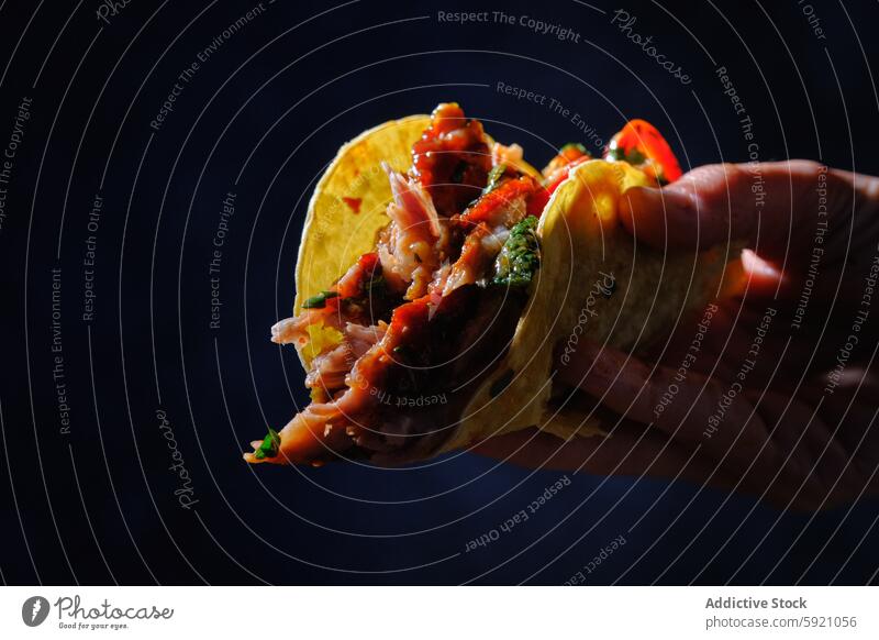 Close-up of woman's hand holding a rib taco food mexican savory meat greens sauce dark close-up eating meal snack cuisine unrecognizable anonymous faceless grip