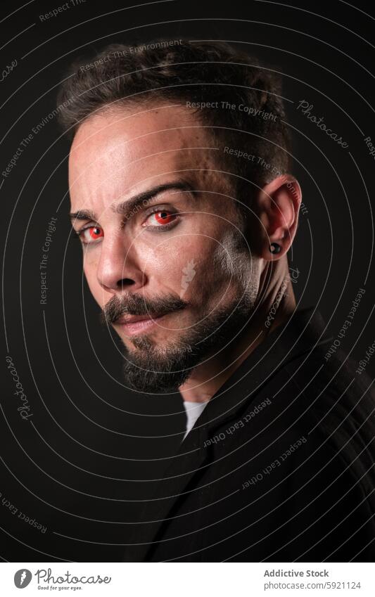 Mysterious Man with Red Eyes in Dark Ambience and red contact lenses man mysterious red eyes goatee piercing look camera dark ambience portrait intense stare