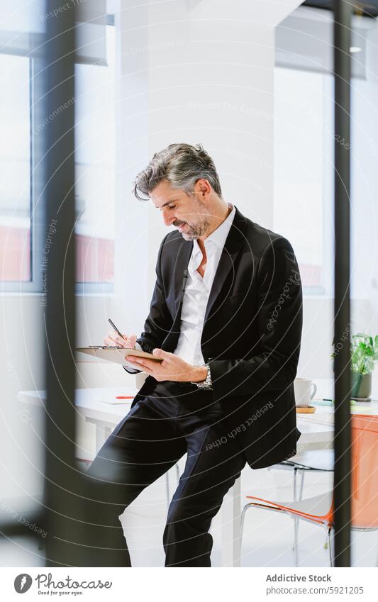 A focused executive in a sharp suit is busy at work, intently reviewing documents in a well-lit, contemporary office space man business professional reading